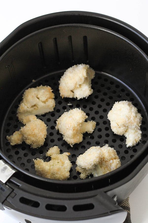 cauliflower pieces in an air fryer basket. 