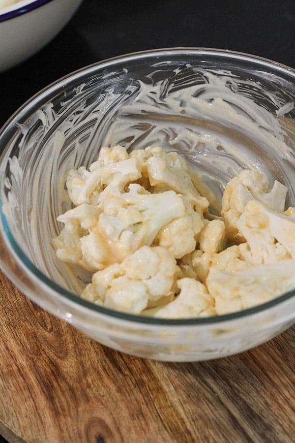 cauliflower pieces in a glass bowls covered in mayonnaise.
