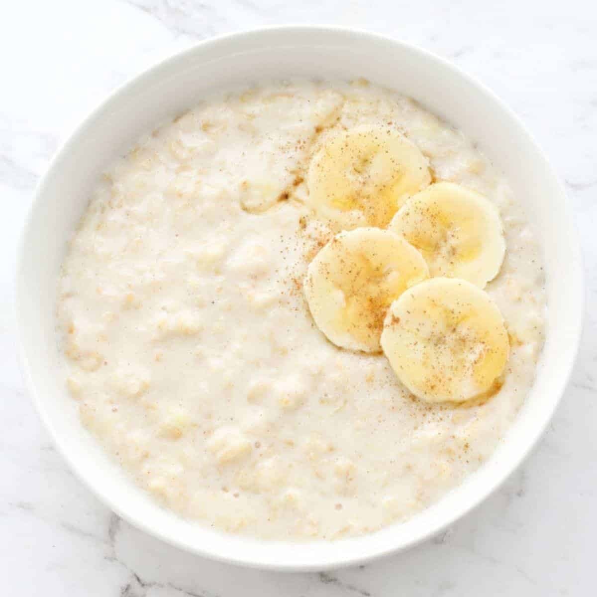 porridge in a white bowl topped with banana slices.