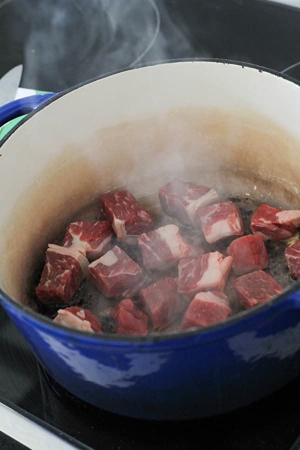 cubes of beef cooking in a dutch oven.