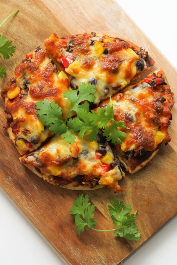 pizza cut into quarters on a wooden board.