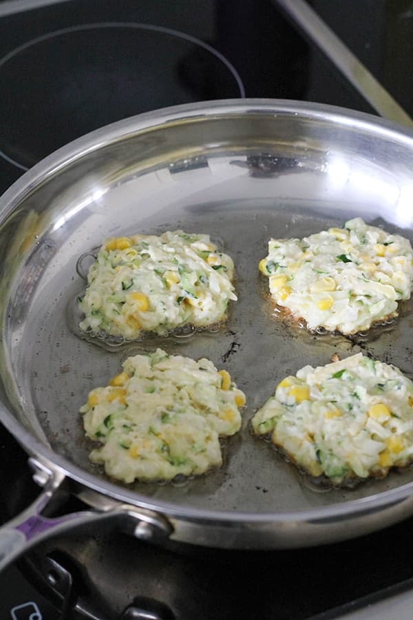fritters cooking in a frying pan.