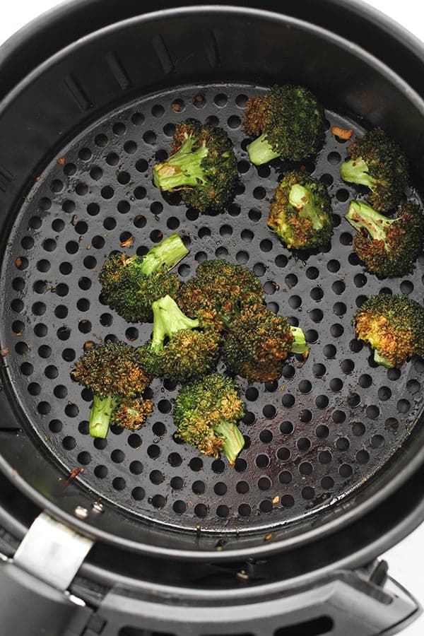 roasted broccoli in an air fryer basket.