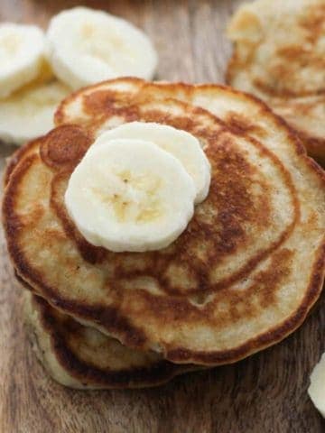 banana pikelets stacked on top of each other on a wooden board.