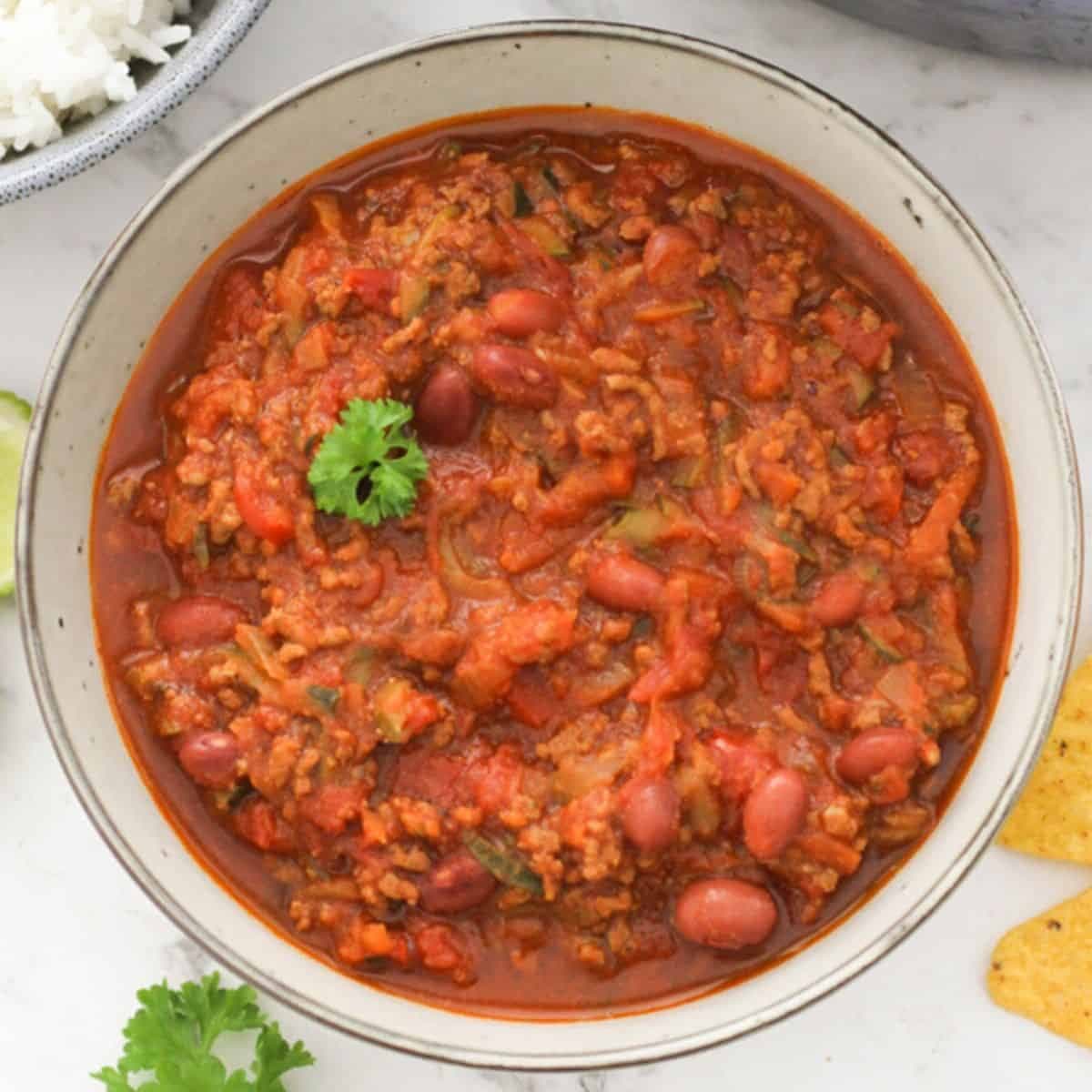 a bowl of chilli con carne topped with parsley.