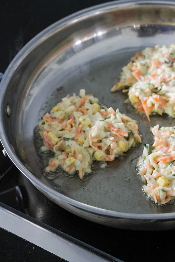 fritters cooking in a frying pan.