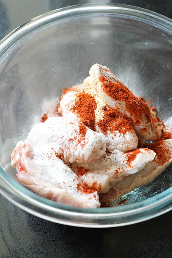 chicken wings in a bowl with baking powder and spices.