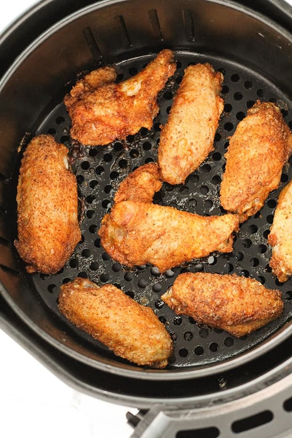 cooked chicken wings in an air fryer basket.