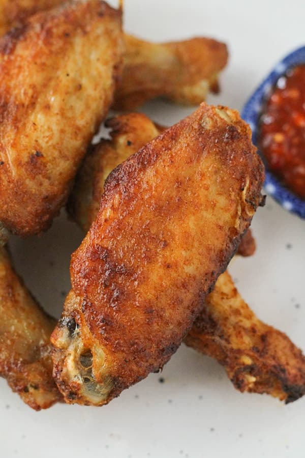 chicken wings in a pile on a white plate.