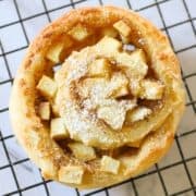 an apple cinnamon roll sitting on a wire rack.