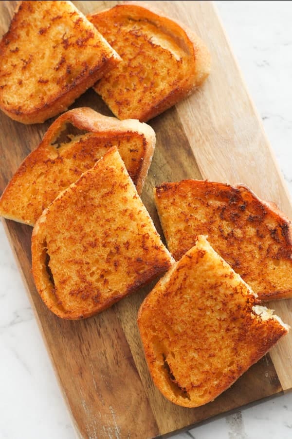 slices of cheese toast on a wooden serving board.