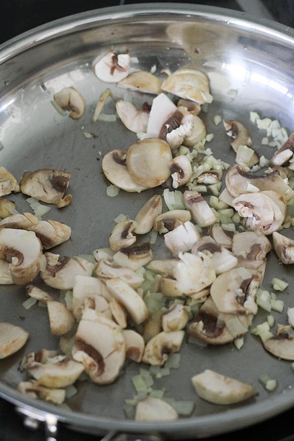 mushrooms and onion in a frying pan.