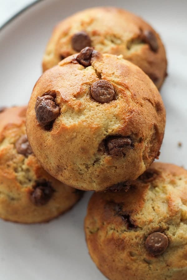 one banana muffins piled on top of each other on a white plate.