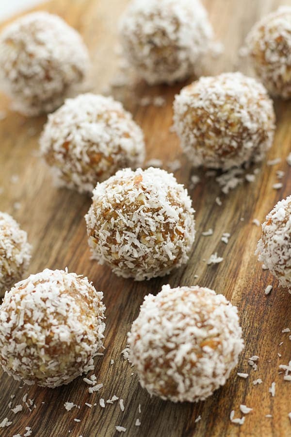 coconut date balls on a wooden board.