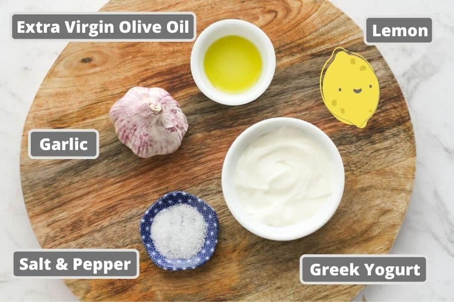 ingredients for garlic yogurt sauce on a wooden board.