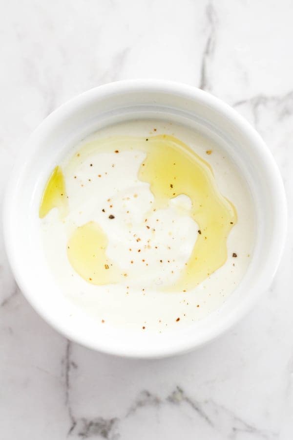 garlic sauce in a white bowl with oil drizzled on top.