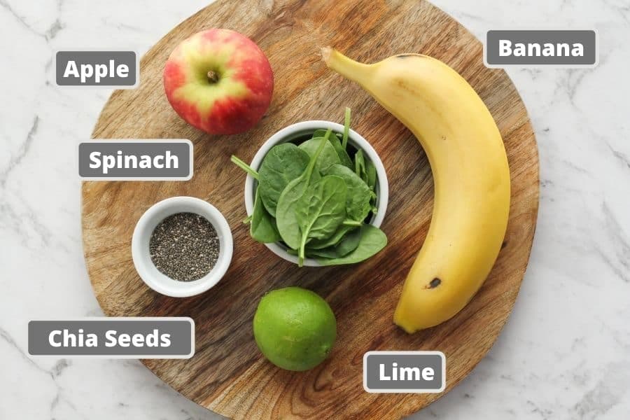 ingredients for spinach apple smoothie on a wooden board.