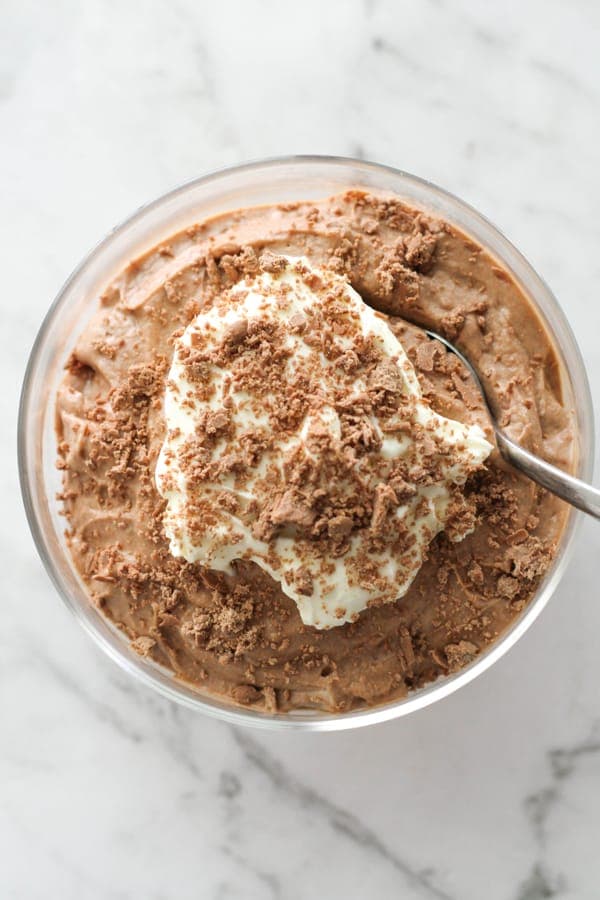 chocolate mousse in a glass topped with whipped cream and grated chocolate.