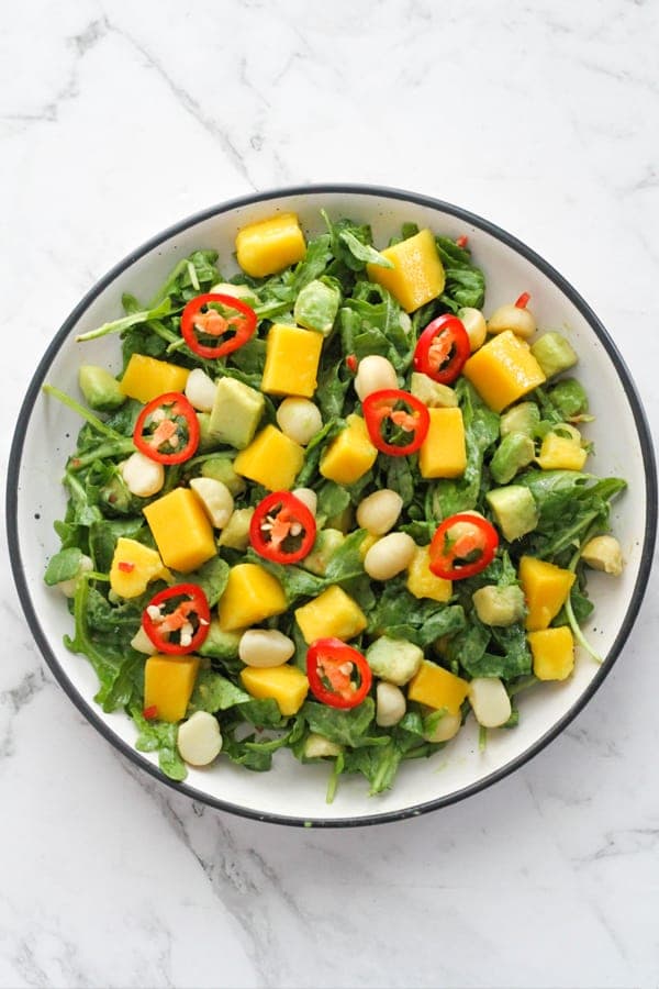 mango avocado salad in a white bowl topped with chilli slices.