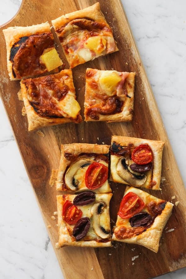 sliced puff pastry pizzas on a serving board.