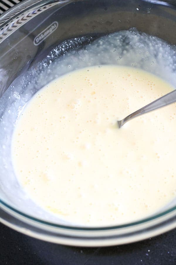 egg and cream mixed together in a glass bowl.