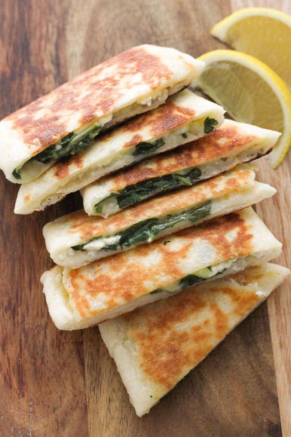 slices of spinach and feta gozleme on a wooden board.