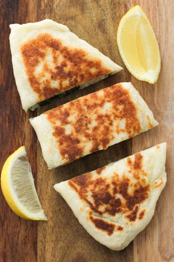 spinach and feta gozleme on a wooden board.