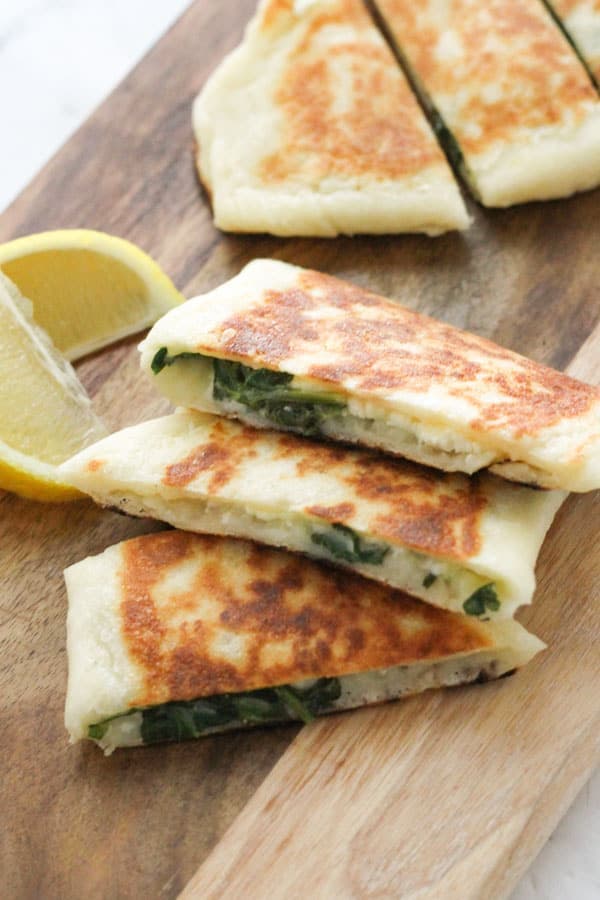 slices of spinach and feta gozleme on a wooden board.