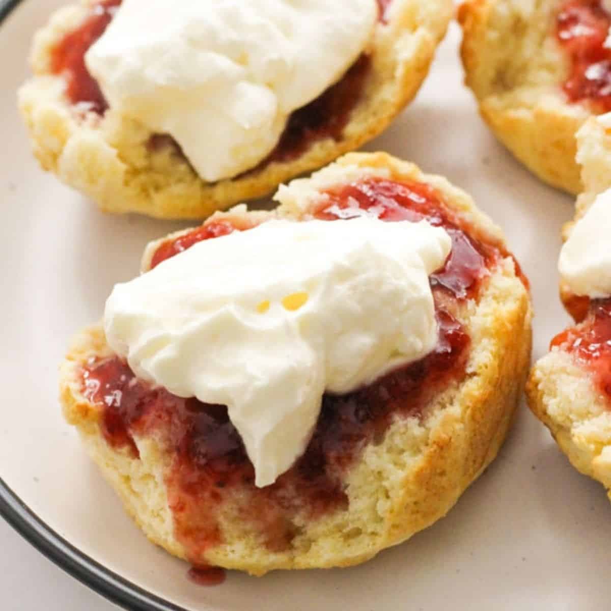 scone topped with jam and cream on a white plate.