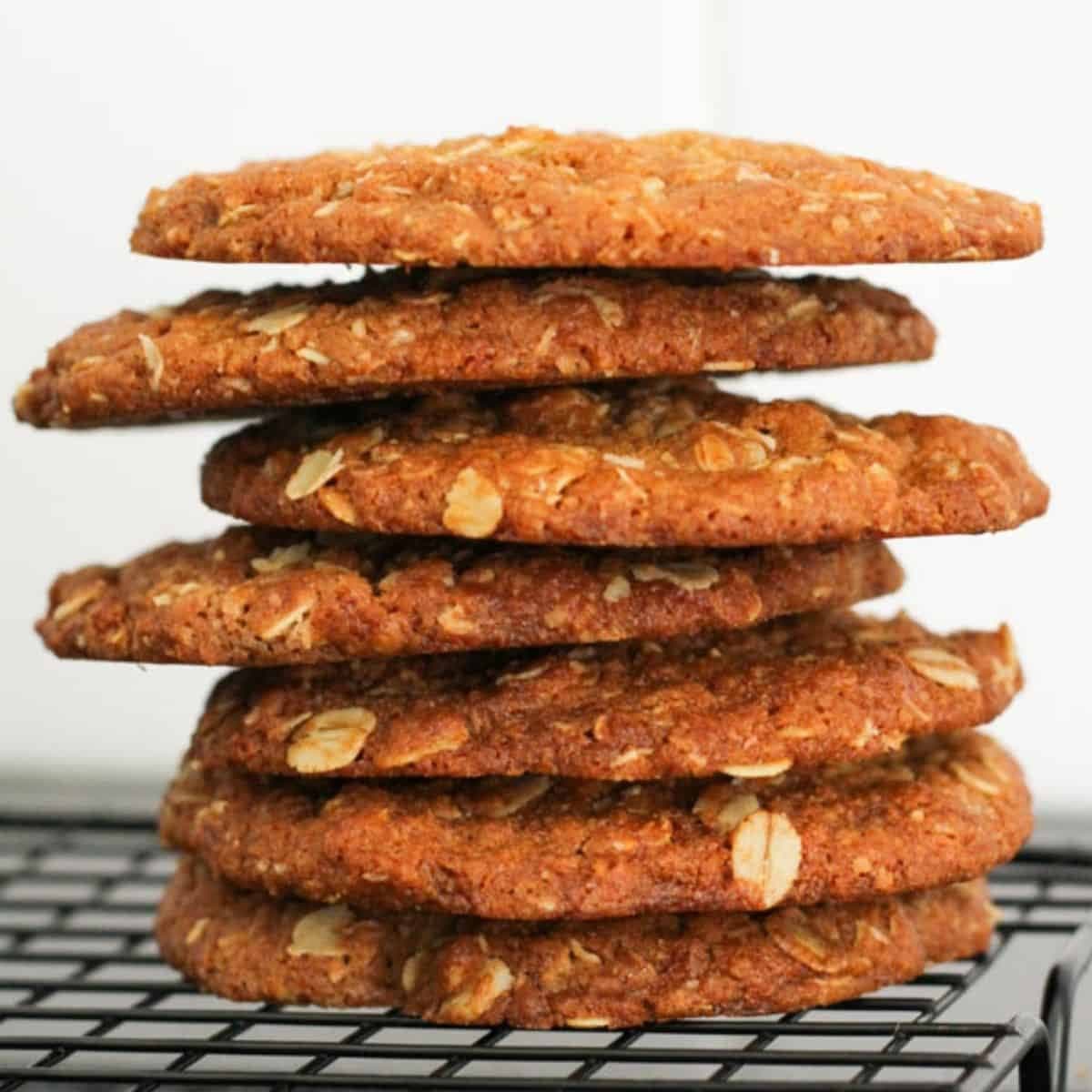 anzac biscuits stacked together on a wire rack.