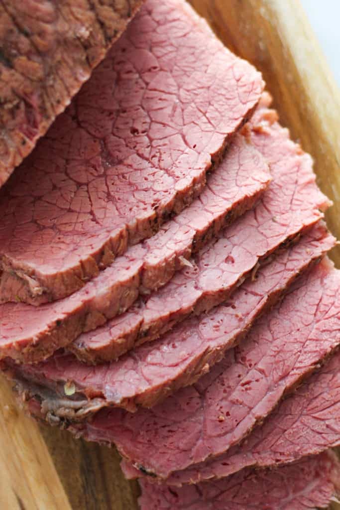 slices of corned beef on a wooden serving board.