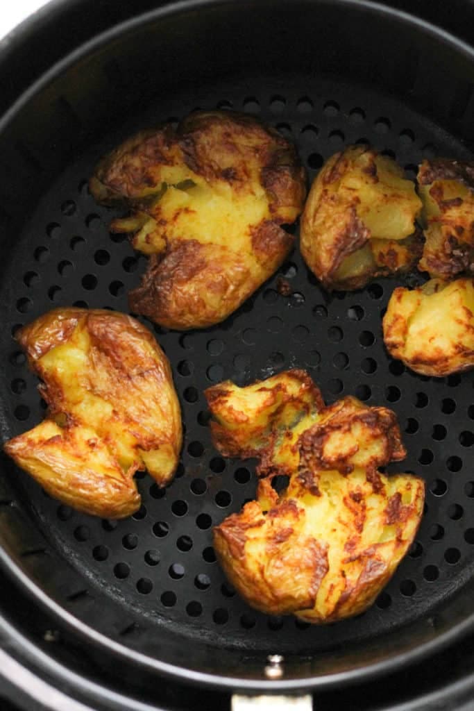 smashed potatoes in an air fryer basket.