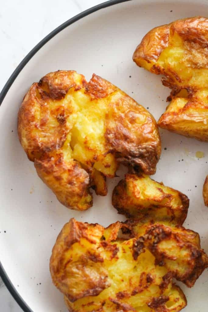 crispy smashed potatoes on a white plate.