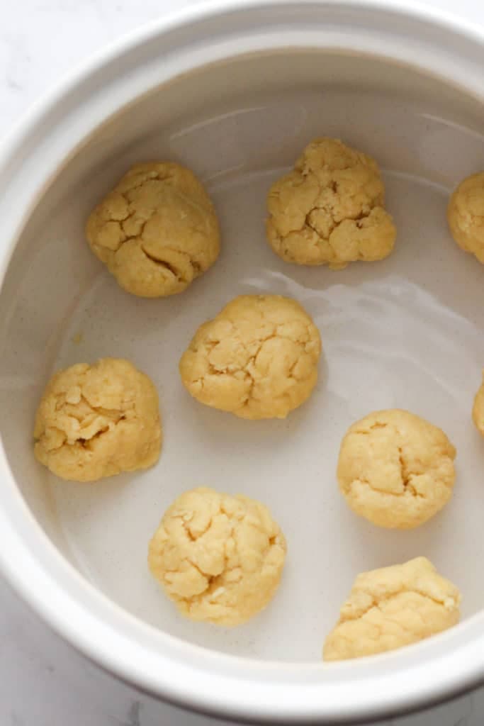 dumpling batter rolled into balls in a baking dish.