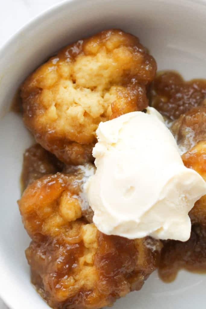 caramel dumplings with ice cream on top in a white bowl.