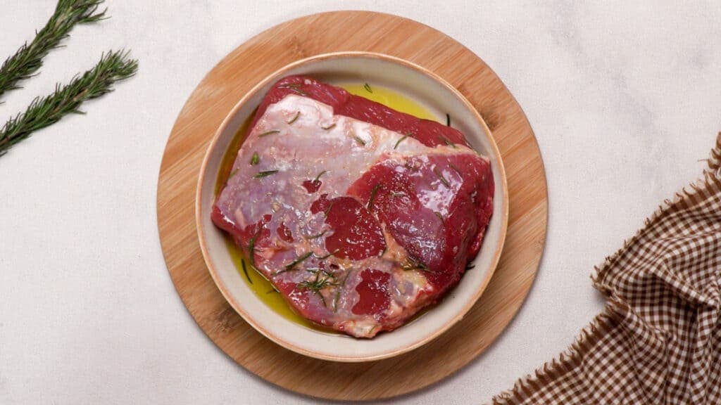 The beef on the plate is mixed with the oil-herb mixture