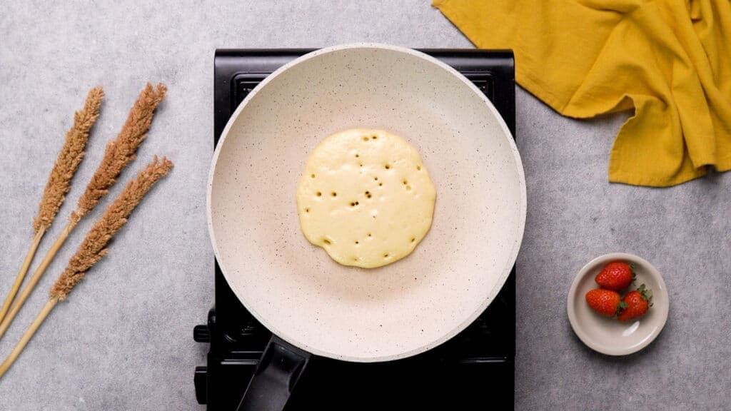 Protein pancakes with tiny bubbles on non-stick pan
