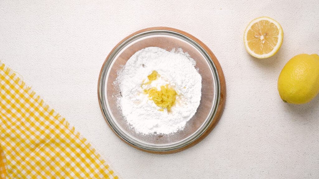 Powdered sugar, lemon juice and lemon in mixing bowl