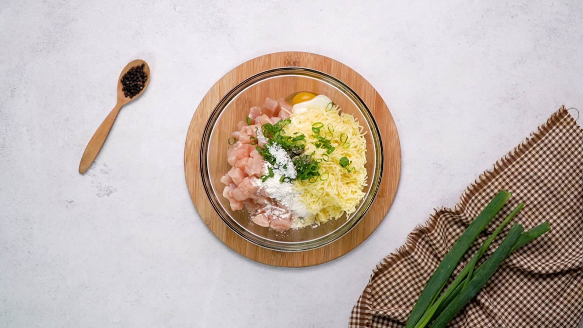 Place the diced chicken into a large mixing bowl along with the remaining batter ingredients: eggs, greek yogurt, flour, shredded cheddar cheese, green onion, salt, and black pepper.