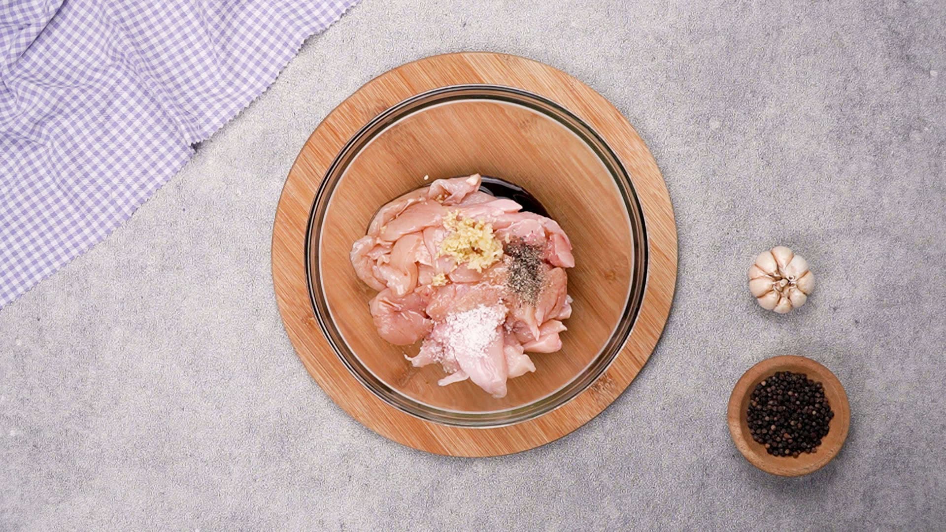 Start by preparing the chicken. In a mixing bowl, combine the chicken strips with soy sauce, minced garlic, grated ginger, kosher salt, ground black pepper, and sake (or mirin).