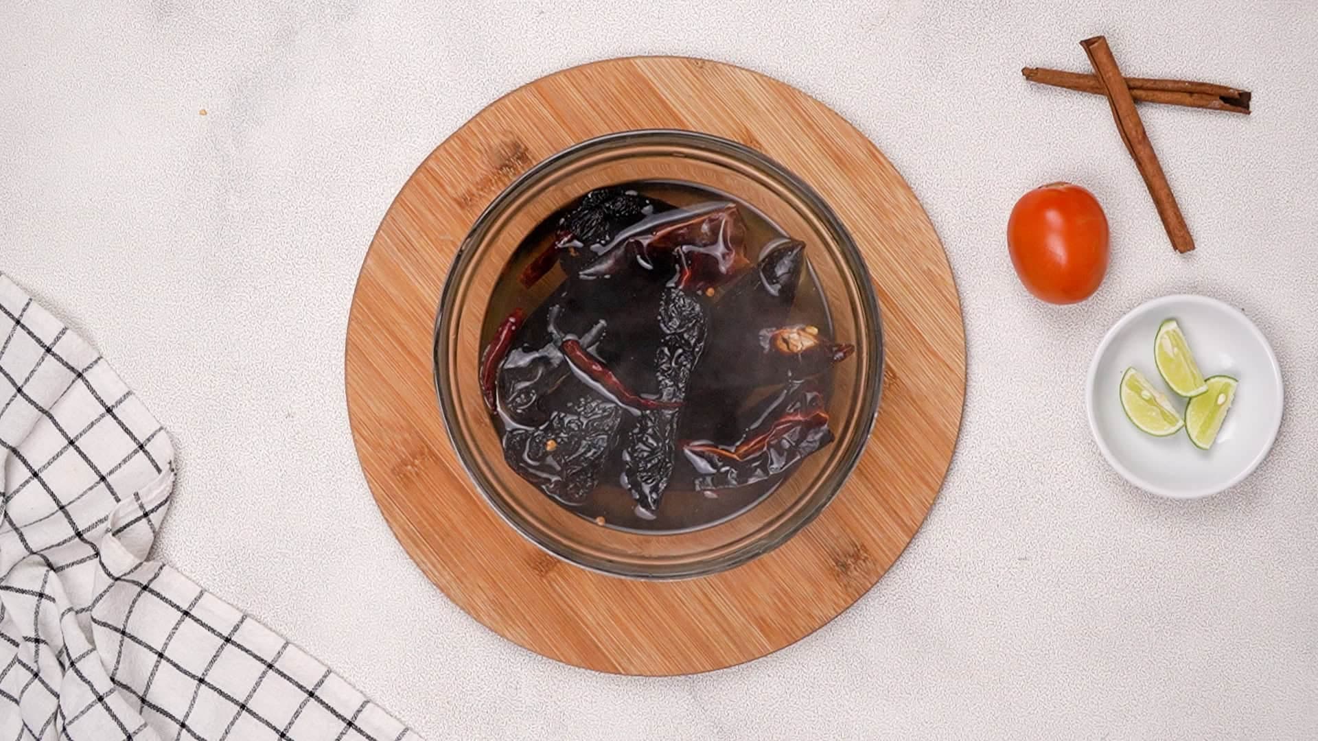 Start by rehydrating the chiles. Place them in a bowl with 3 cups of boiling water and let them soak for 20 minutes.