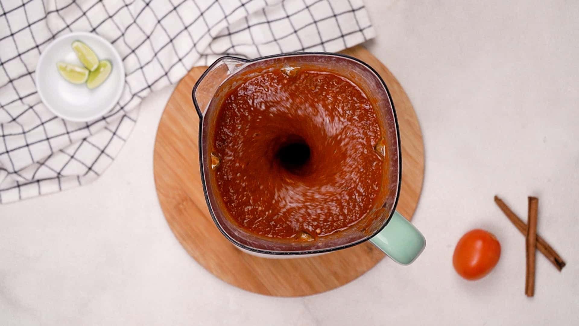 Blend the chiles, tomatoes, onion, garlic, soaking water, oregano, salt, cumin, black pepper, cinnamon, and apple cider vinegar together in a blender until the mixture is smooth and well combined.