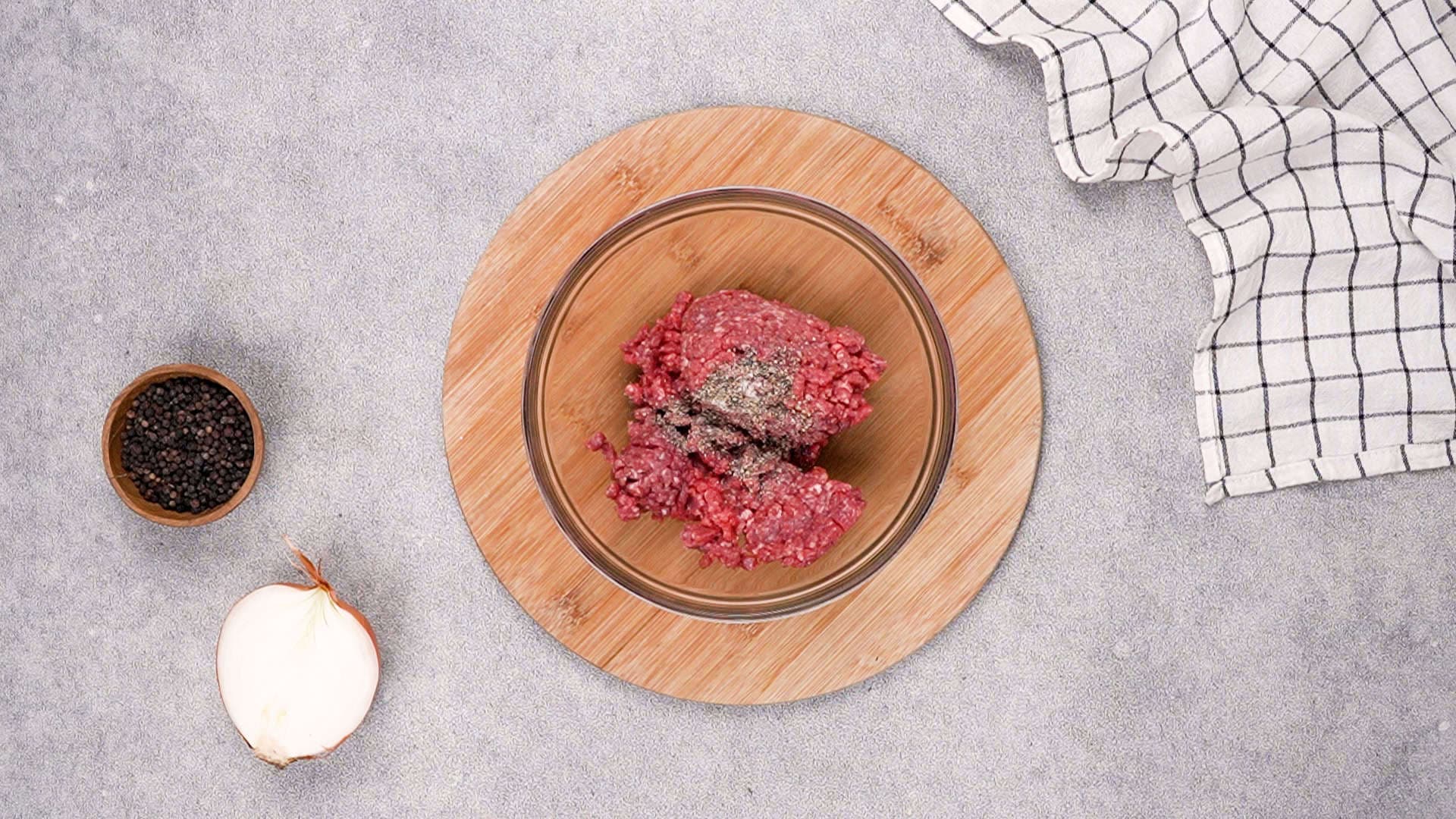 After that, in a mixing bowl, season the ground beef with salt and black pepper.