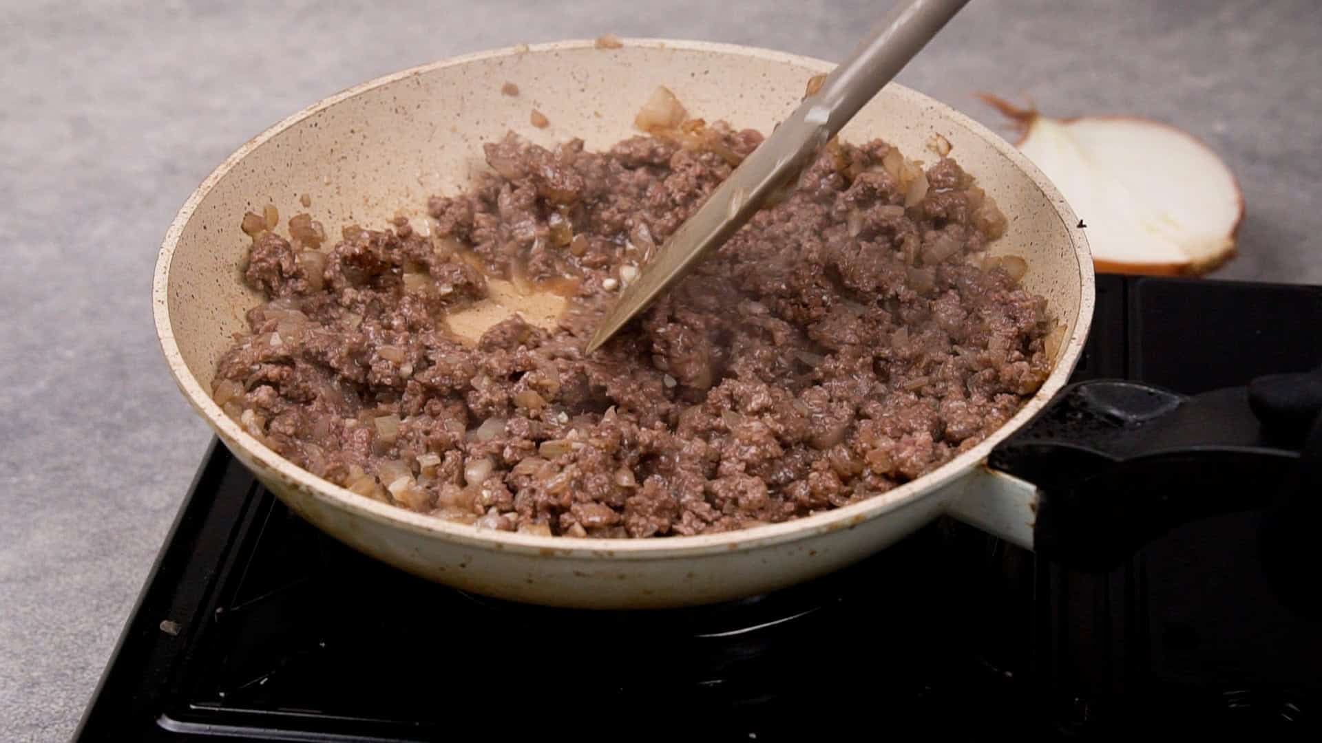 Add the seasoned ground beef to the skillet, breaking it apart with a spatula as it cooks.