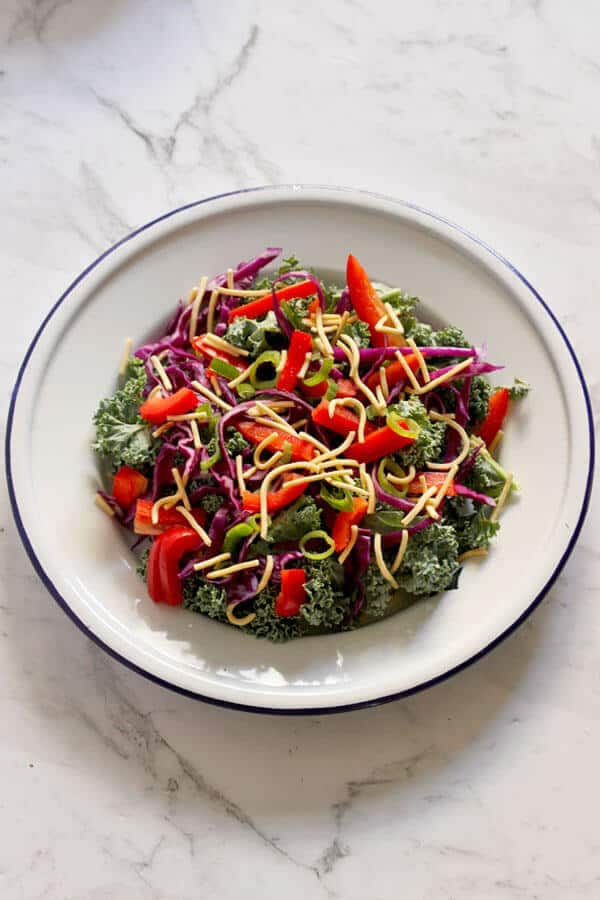 crunchy kale salad with lemon tamari dressing on a white plate