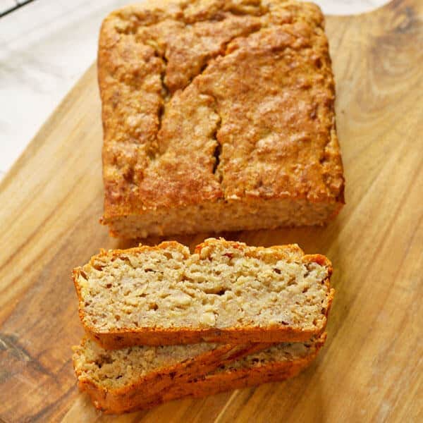 slices of healthy banana bread stacked on top of each other with the loaf sitting behind