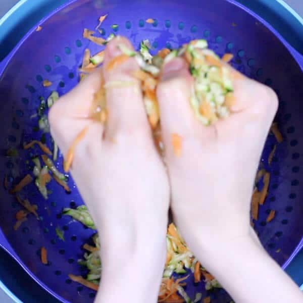 hands squeezing shredded carrot and zucchini