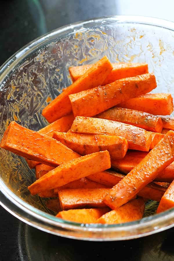wedges in a glass bowl covered in oil and spices.
