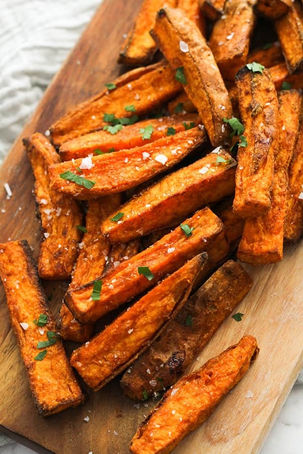 sweet potato wedges covered in salt on a wooden serving bowl.