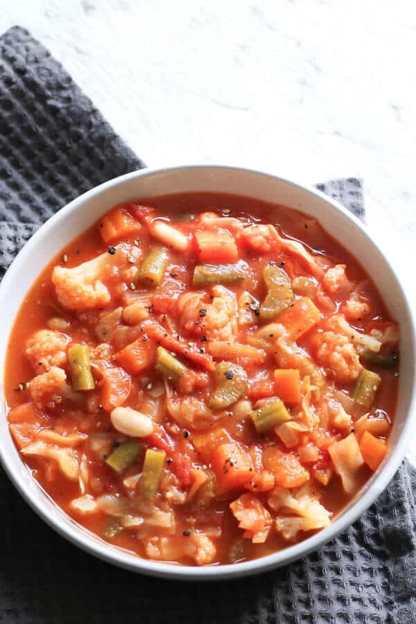 cannellini bean soup in a white bowl on a grey napkin